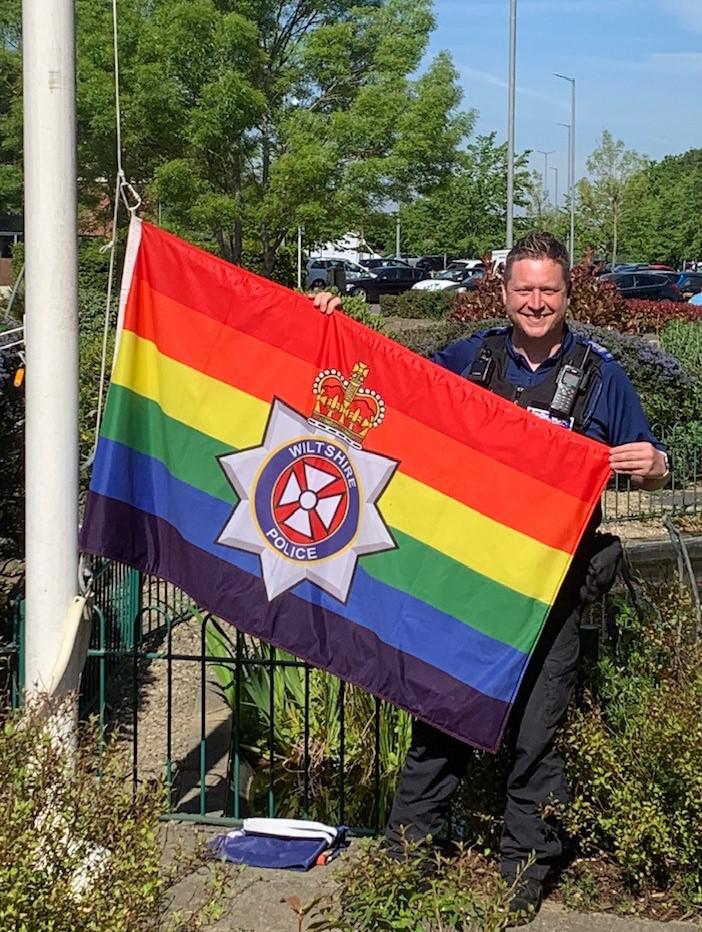 PCSO Lee Hare unfurling the Pride flag at Gablecross Police Station in Swindon