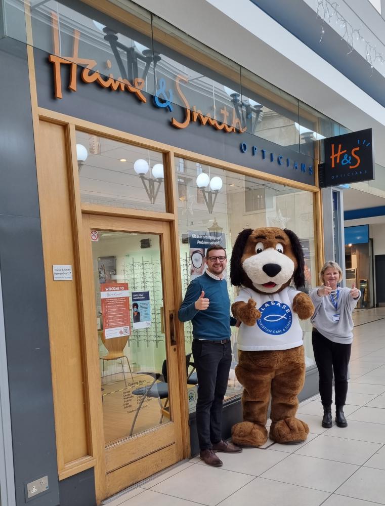 L-R Tom Adams, business change and improvement manager at Haine & Smith: Roofus, Alabaré mascot: Nicky Matthews, deputy marketing manager at Alabaré, outside the Trowbridge practice