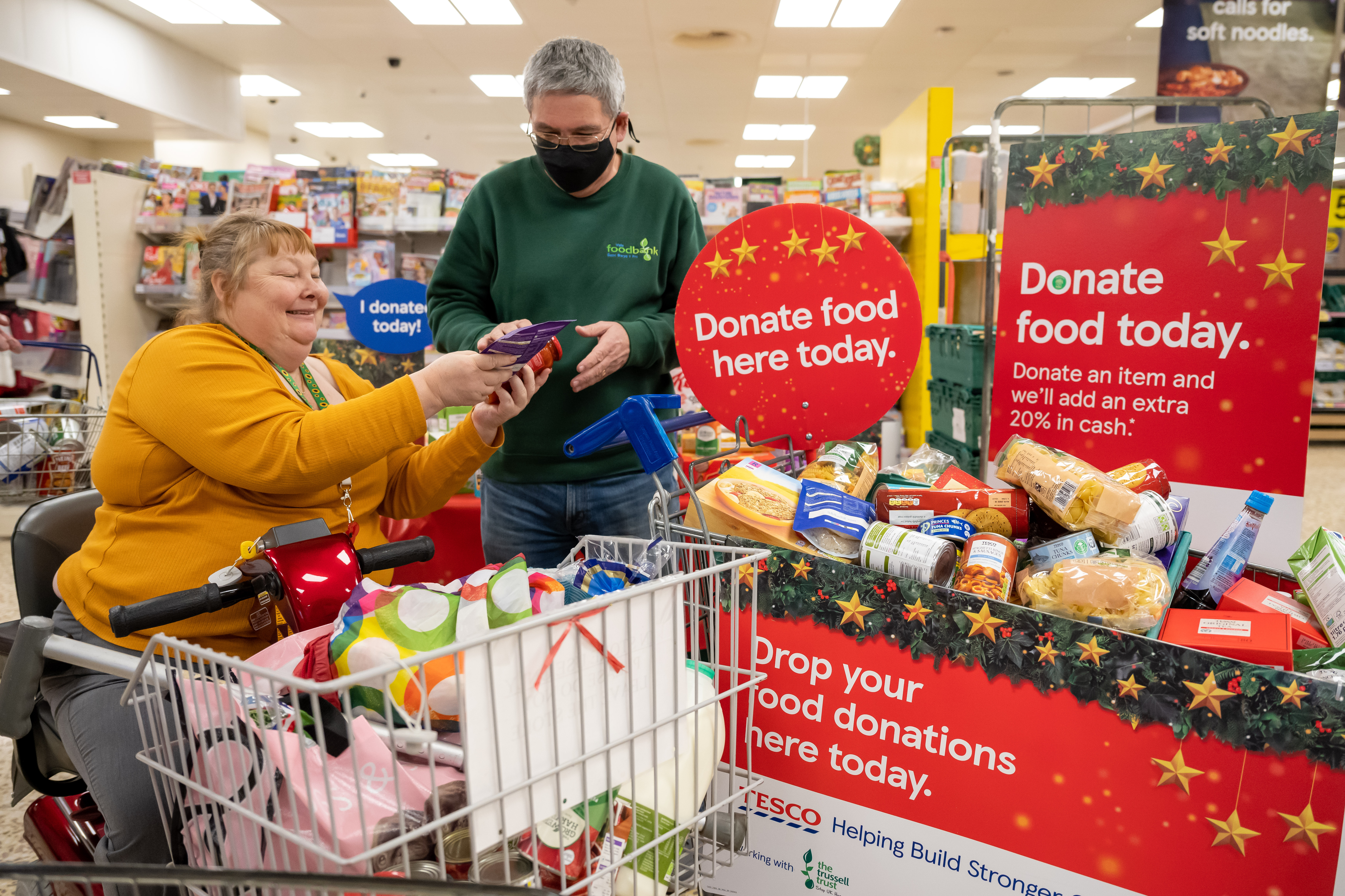 A volunteer accepts a donation from a Tesco customer