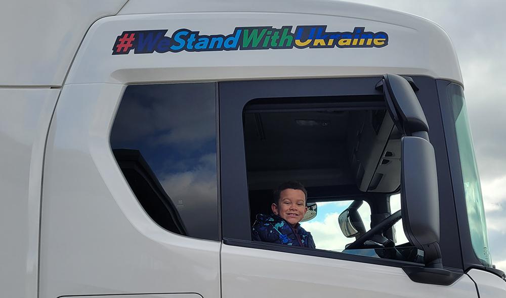 Young aid collector Marshall Murapa samples the view from the lorry's cab