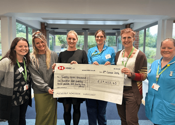Becky’s daughters handing a cheque to Prospect Hospice