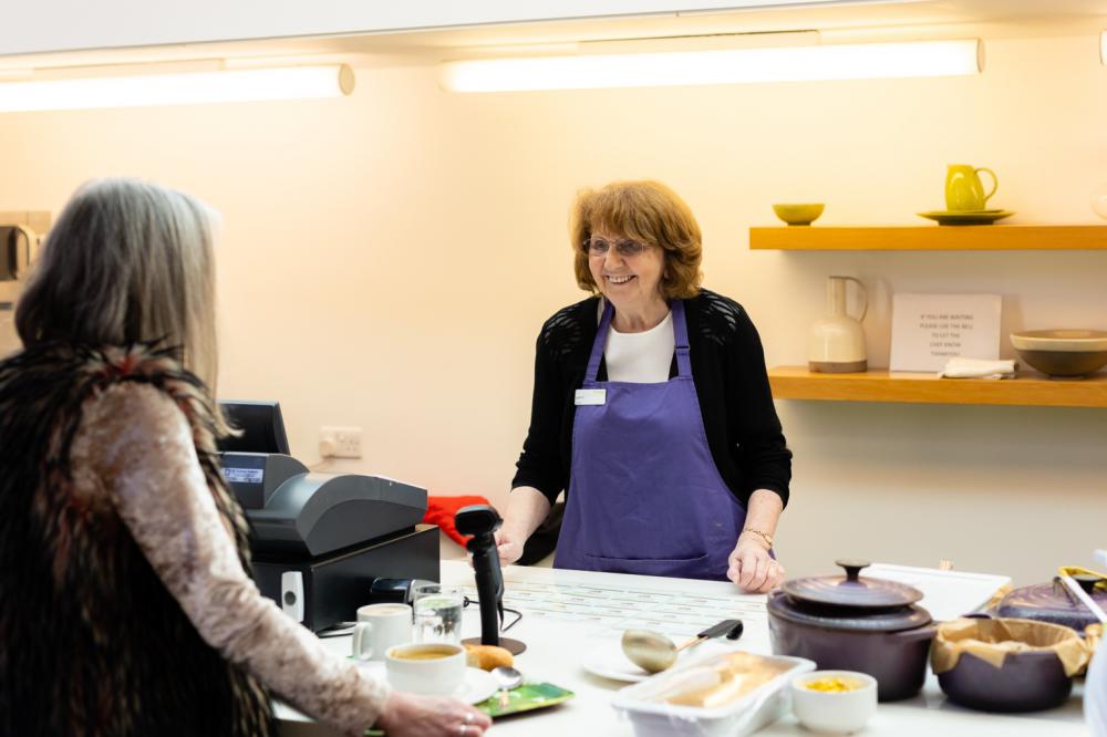 A volunteer staff member serving a customer in the Heart of the Hospice cafe