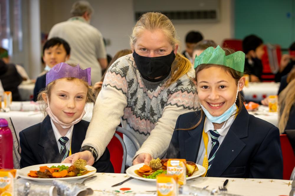 Assistant Headteacher Helga Maddock serves lunch to year 7 pupils Freya and Emma