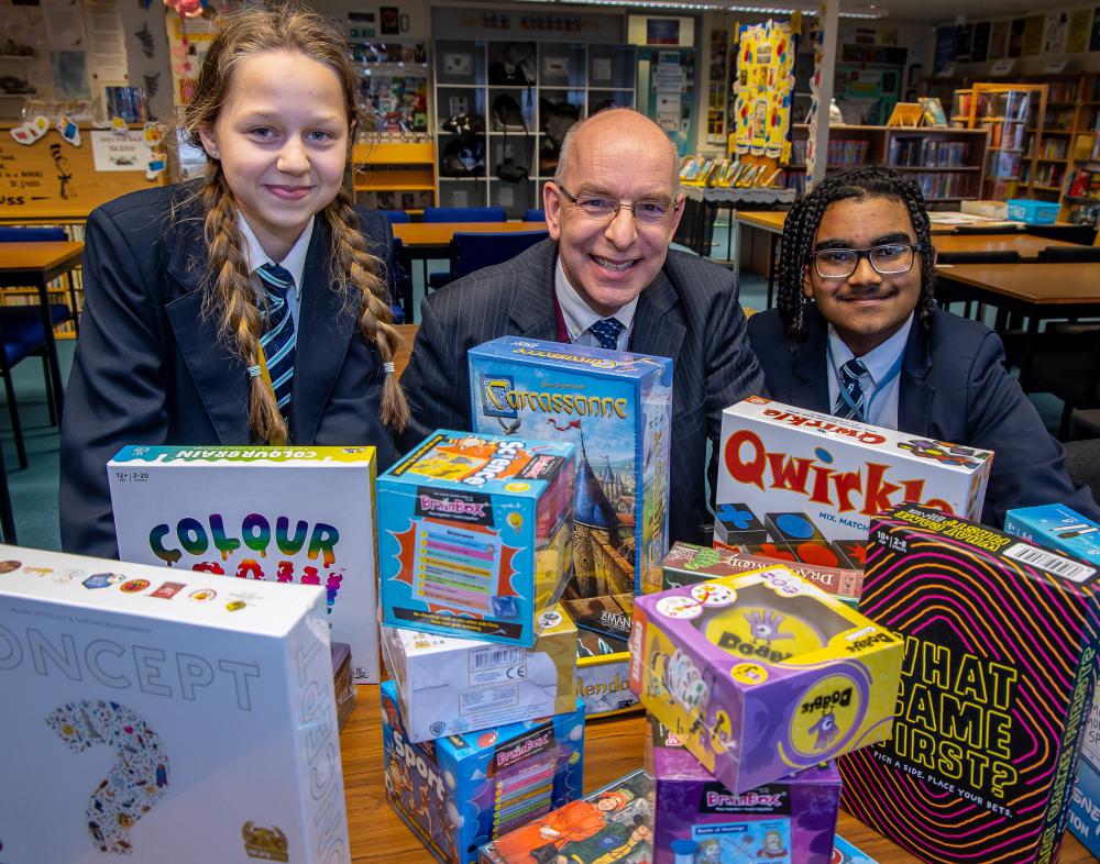 Lawn Manor Academy students Katie & Eifion pictured with the trust's Chair of Governors Nathan Coombs holding some of the games which have been donated by Zatu Games