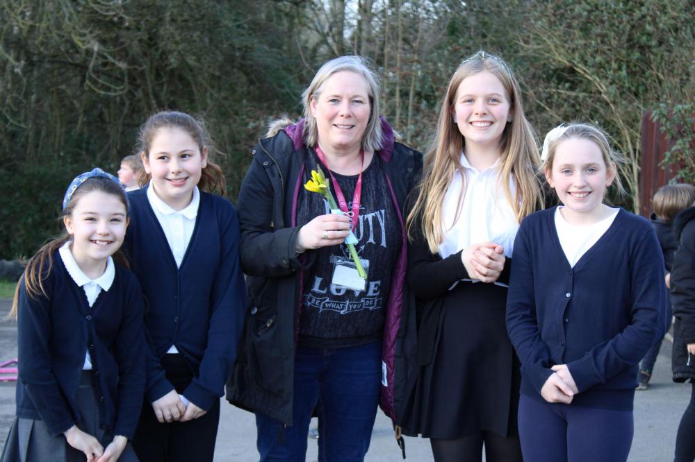 Year 6 ambassadors giving daffodils to lunch staff